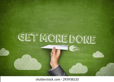 Get more done concept on green blackboard with businessman hand holding paper plane