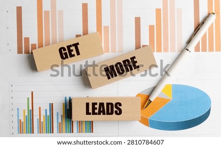 Get more leads message on wooden blocks with business charts and pen representing lead generation marketing growth.