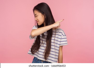 Get out, leave me! Portrait of irritated dissatisfied brunette girl in striped t-shirt showing way out, ordering to go away, feeling betrayed and vexed. indoor studio shot isolated on pink background