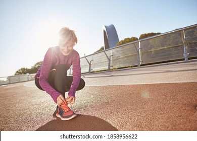 Get Ready. Full Length Shot Of Active Mature Woman Wearing Sportswear Tying Shoelaces On Sporty Sneakers While Getting Ready For Running Outdoors On A Sunny Day