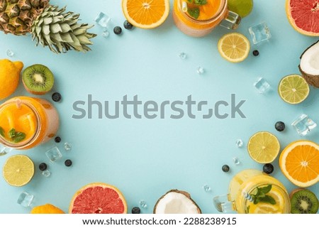 Get ready for a summer blast with this top view flat lay of citrus juices and cocktails made with fresh oranges, lemons, limes, and grapefruits, ananas on pastel blue backdrop with an empty space