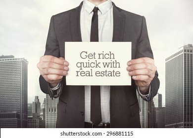 Get Rich Quick With Real Estate On Paper What Businessman Is Holding On Cityscape Background