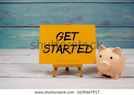 Get Started text written on paper card with piggy bank on wooden background