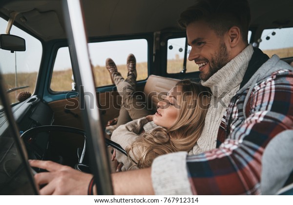 Getting\
away from it all... Attractive young woman resting and smiling\
while her boyfriend driving retro style mini\
van