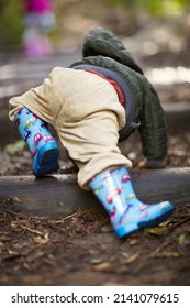 Getting back down to earth. Rearview of a young boy crawling in the dirt wearing gumboots.