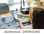 Getting chores done quicker together. Cropped shot of little daughter washing dishes together at home.