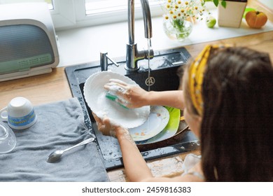 Getting chores done quicker together. Cropped shot of little daughter washing dishes together at home. - Powered by Shutterstock