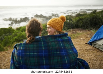 Getting comfy at the campsite. Rearview shot of an affectionate young couple wrapped in a blanket at their campsite. - Shutterstock ID 2275452681