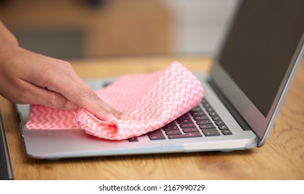 Getting in the crevices. Shot of a woman cleaning the dust from the laptop keyboard.