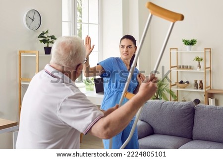 Its getting dangerous in here. Angry, aggressive, bad tempered senior patient fighting with medical worker. Old man becomes uncontrollable and threatens scared nurse or volunteer medic with crutch