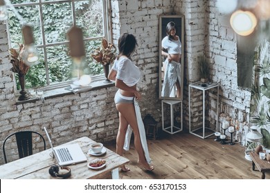 Getting Dressed. Full Length Rear View Of Attractive Young Woman Looking In The Mirror While Trying On Her Jeans