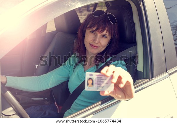 Getting a driver\'s license, a beautiful driving\
girl shows a new driver\'s\
license