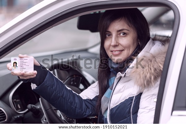 Getting a driver\'s\
license, female hands show US driving license, amid the steering\
wheel of a car, toned