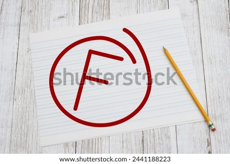  Getting a failing grade F on ruled lined paper with pencil for school on weathered wood deak