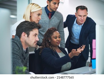 Getting feedback from her team. Cropped shot of a group of corporate colleagues gathered around a computer in their office.