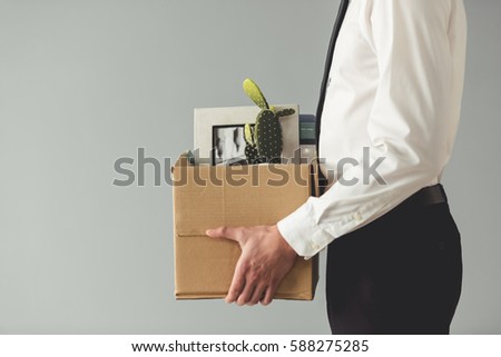 Getting fired. Cropped image of handsome businessman in formal wear holding a box with his stuff, on gray background Foto d'archivio © 
