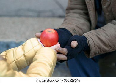 Getting Food. Kind Little Child Gives Apple To A Homeless Person.