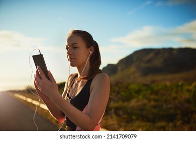 Getting Her Workout Tracks Ready. Shot Of A Sporty Young Woman Organizing Her Workout Playlist Outdoors.