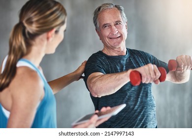 Getting Older, Getting Fitter, Getting Stronger. Shot Of A Senior Man Using Weights With The Help Of A Physical Therapist.