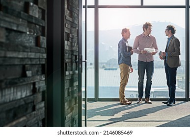 Getting Organized Before The Presentation. Shot Of Male Coworkers Talking While Standing In Front Of A Window In An Office.