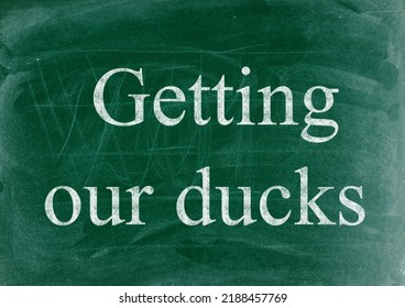 Getting Our Ducks In A Row Business Phrase Written In Chalk On A Blackboard