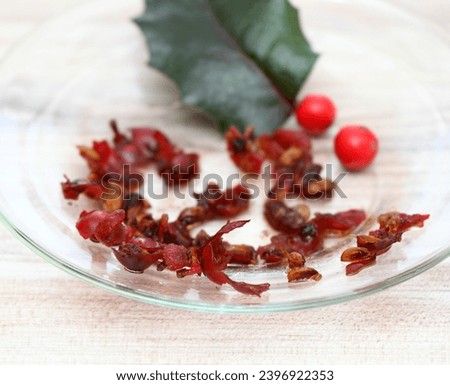 Getting own seeds from berries. Glass plate with squashed red holly berries and seeds, dried seeds next. 