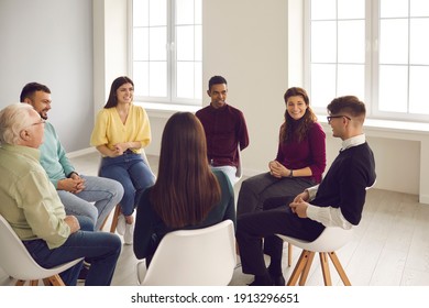 Getting psychological help in a friendly atmosphere. Happy smiling diverse people sitting in circle and listening to young man talking about his concerns and sharing opinion in a group therapy session - Powered by Shutterstock