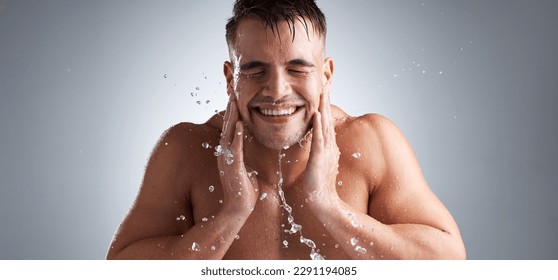 Getting ready for the day. Studio shot of a handsome young man washing his face against a grey background.