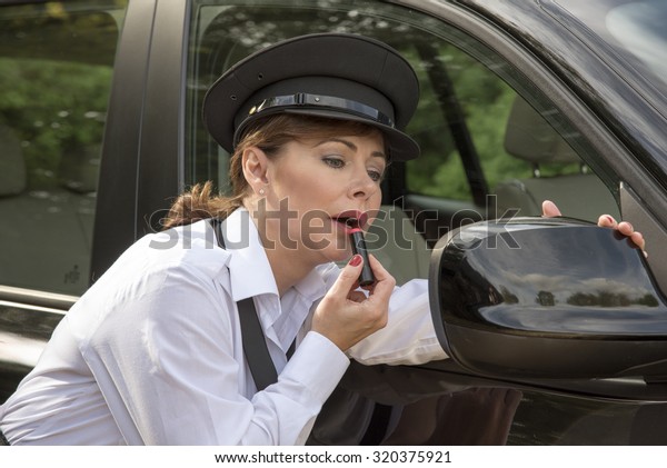 Getting ready for driving a woman chauffeur\
applying makeup