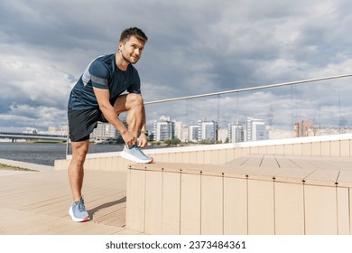 Getting ready for the start corrects running shoes for training. Cardio is a hardy man.  Mental and psychological health when working with fitness exercises. Background sky blue clear day.n - Powered by Shutterstock