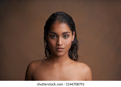 Getting ready for the world. Studio shot of a beautiful young woman against a brown background.