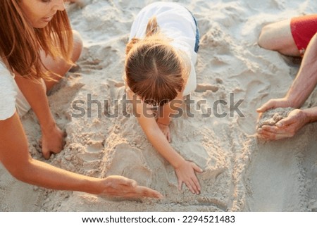 Getting the sand in our toes. Shot of a family drawing shapes in the beach sand together.
