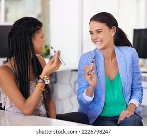 Getting their fix electronically. Shot of businesswomen smoking electronic cigarettes in the office.