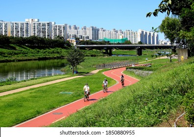 Geumcheon-gu, Seoul, South Korea - September 13, 2020: People are riding bicycles on bike lane near Anyangcheon Stream with the background of highrise apartments