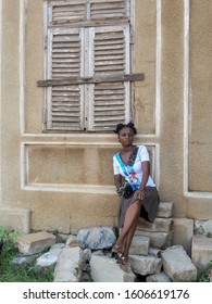 Ghana Woman Sitting Among Ruins Of A House From England's Colonization Photo Taken In Ada Foah Ghana West Africa 2017 December 5.