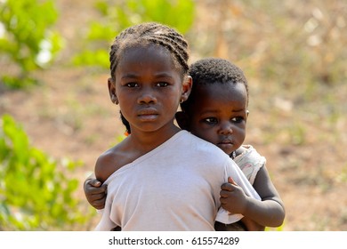 GHANI, GHANA - JAN 14, 2017: Unidentified Ghanaian little girl carries a baby on her back in the Ghani village. Ghana children suffer of poverty due to the bad economy.