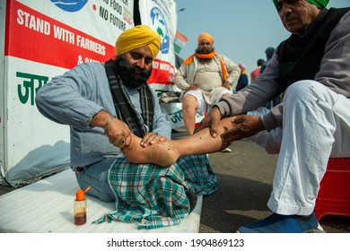 Ghaziabad, Uttar Pradesh, India, January 23 2021: Sikh Man Doing Foot Massage Work As A Volunteer During India Farmer Protest Area At Ghazipur.