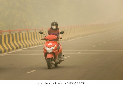 Ghaziabad, Uttar Pradesh/India-  Nov 3  2019 : woman with mask ridding bike during smog in air , smoke coming from Haryana and Punjab, north India's states