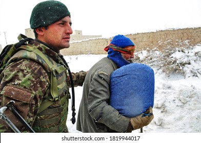 GHAZNI, AFGHANISTAN - FEBRUARY 2011: Afghan National Army Soldier Helps Elderly Man Walk To His Home During A Dismounted Patrol.