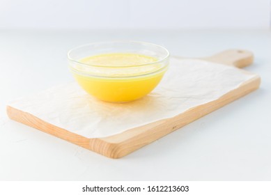 Ghee butter in a bowl on a wooden board.