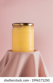 Ghee or clarified butter in jar on pink background. Minimal style. Scene with geometric shapes. Copy space.