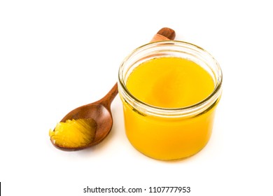 Ghee or clarified butter in jar and wooden spoon isolated on white background