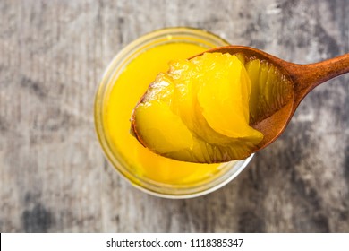 Ghee or clarified butter in jar and wooden spoon on wooden table. Top view