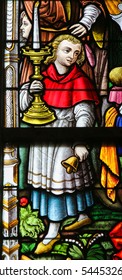 GHENT, BELGIUM - DECEMBER 23, 2016: Stained Glass window depicting an Altar Boy holding a Candelabrum in the Cathedral of Saint Bavo in Ghent, Flanders, Belgium.