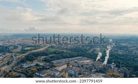 Ghent, Belgium. Sun rays and beautiful clouds. On the ground, a suburb of the city of Ghent with an industrial area and a railway, small houses. Ringvaart in Ghent - water channel, Aerial View  