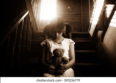 Ghost girl in haunted house holding teddy bear,Mysterious girl in white dress sitting on stairway in abandon house