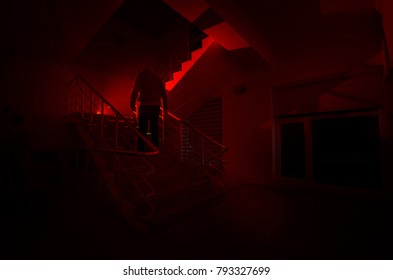 Ghost In Haunted House At Stairs, Mysterious Silhouette Of Ghost Man With Light At Stairs, Horror Scene Of Scary Ghost Spooky Llights . Scary Hall. Halloween Background.