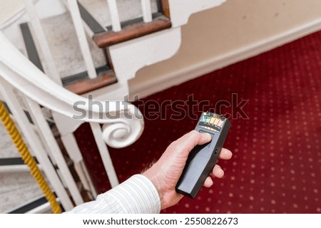 A ghost hunter is seen using an advanced EMF detector to measure of any paranormal activity in an old haunted hotel in the UK.