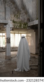 Ghost in a white sheet walking through an abandoned building. Copy space