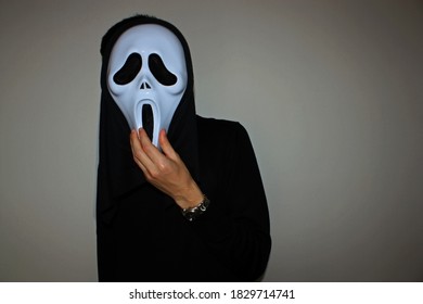 Ghostface mask for Halloween holiday on the adult man's face.